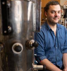 Daniel Suess sits among lab machinery.